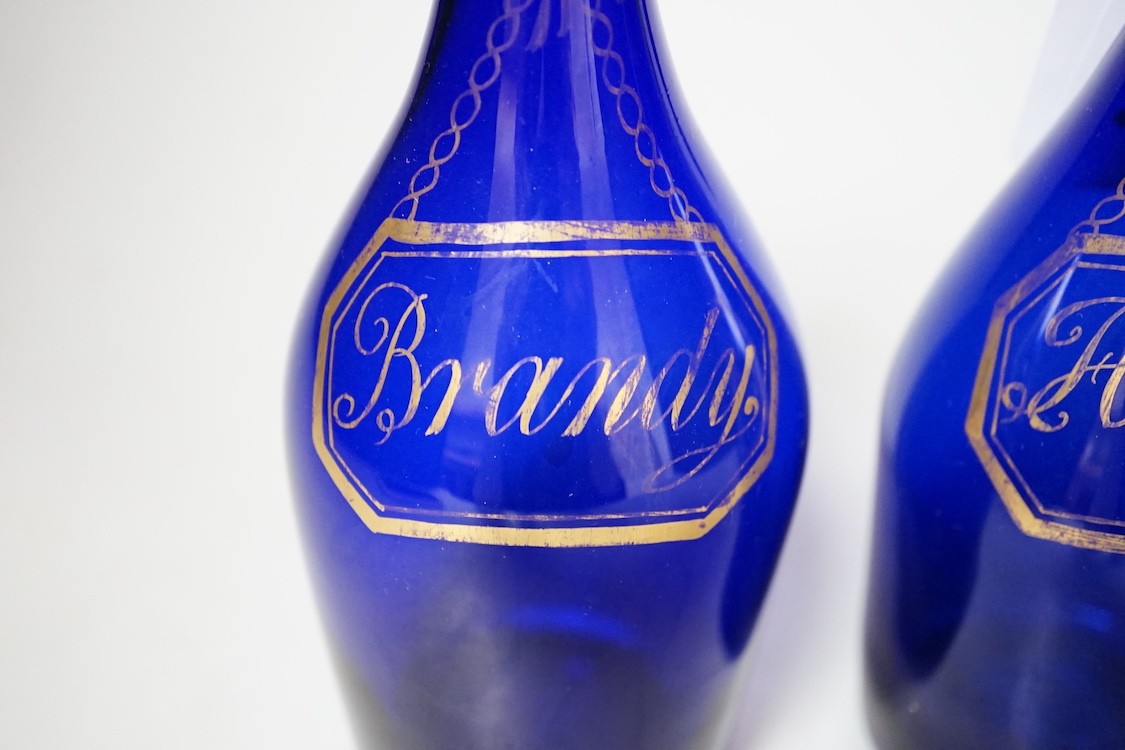 A pair of Regency blue glass decanters, labelled in gilt; Brandy and Hollands, 19cms high not including stoppers